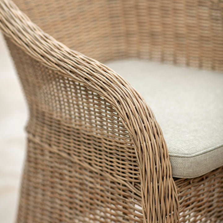 Close-up of a wicker chair with a cushion on a light background